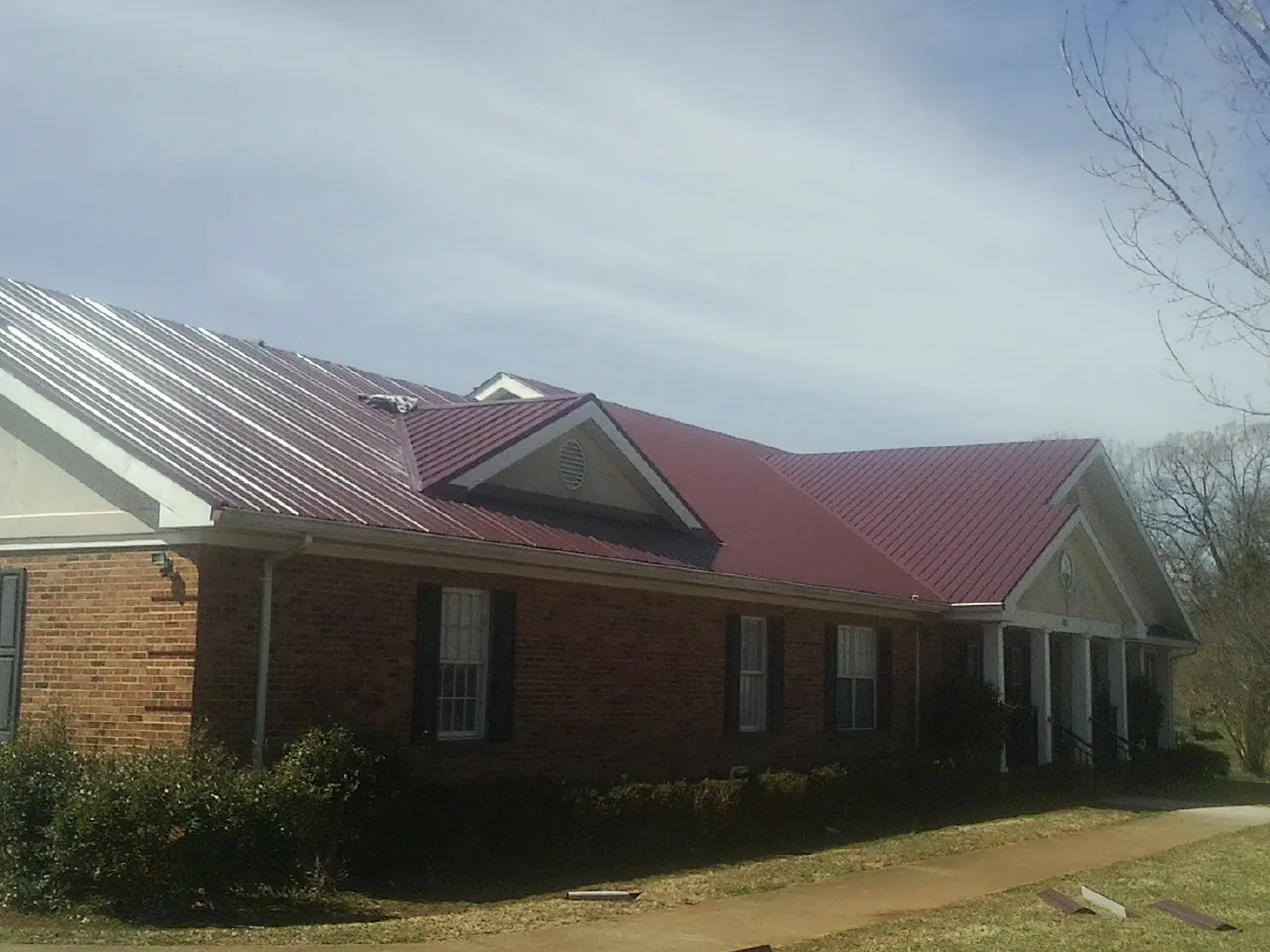 Red metal roof with gabled entries on a long brick building in Black Creek