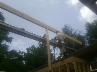 Carpenter setting a ridge beam over a new addition frame — Ice Dam Removal by Roofing Brothers in Black Creek
