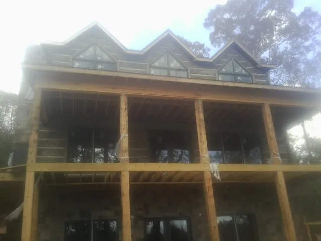 Dormers and porch framing on a large log home under construction — Roof Coating work by our crew in Black Creek