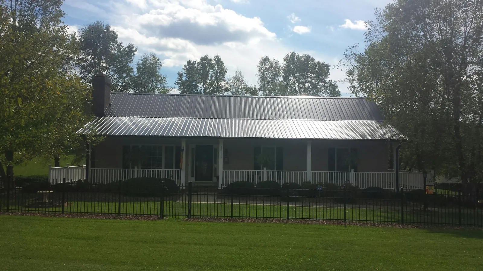 Gray metal roof on a brick ranch with a full width front porch — Gutter Guard Installation work by our crew in Black Creek